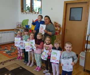 Na zdjęciu widoczne są dzieci trzymające w dłoniach wykonane przez siebie prace plastyczne.