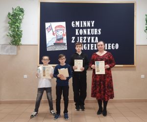 Nauczycielka i trzech uczniów na tle tablicy dekoracyjnej
