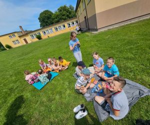 Dzieci siedzą na kocu na pikniku szkolnym
