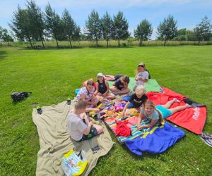 Uczniowie siedzą na kocyku na pikniku