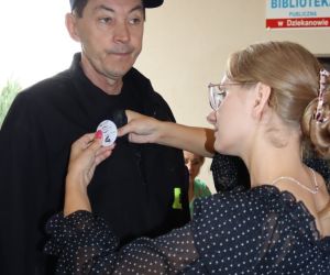 Na zdjęciu kobieta przypina przypinkę mężczyźnie. 