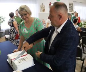 Zdjęcie przedstawia dwie osoby krojące tort.