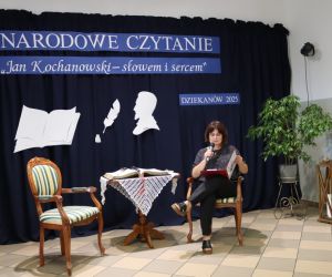 Zdjęcie przedstawia osobę czytającą siedzącą na krześle.