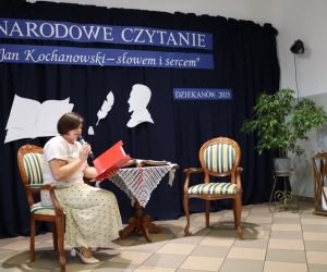 Zdjęcie przedstawia osobę czytającą siedzącą na krześle.