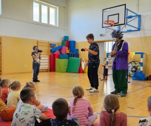 Uczeń trzyma kamerę i filmuje pokaz klauna Waldusia, obok niego inny uczeń uczestniczy w zabawie.
