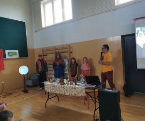 Kilkoro uczniów przebranych w tradycyjne tureckie stroje stoi obok podróżnika, który opowiada z mikrofonem w ręku.