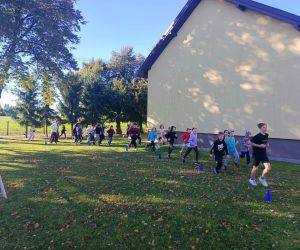 Uczniowie klas młodszych biegną dookoła boiska