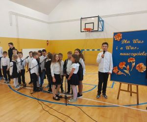 Uczniowie śpiewają stojąc wokół mikrofonów