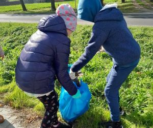 Dwoje uczniów wkłada śmieci do worka