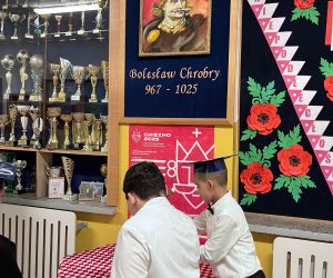 uczniowie składają kwiaty przy wizerunku patrona szkoły