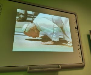 Prezentacja multimedialna-slajd przedstawiajacy Jana Pawła II , który całuje Polską ziemię
