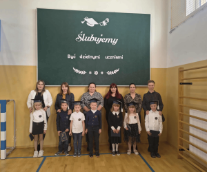 Pierwszoklasiści pozują do zdjęcia z rodzicami.