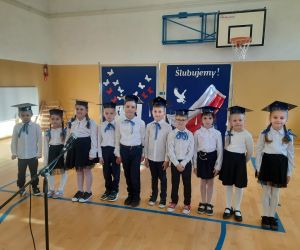 Uczniowie klasy pierwszej na tle tablicy dekoracyjnej