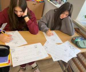 Dwie uczennice rozwiązują przy stoliku łamigłówkę matematyczną