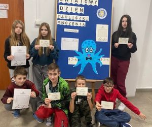Kilkoro uczniów stoi przy dekoracji związanej z Dniem Tabliczki Mnożenia