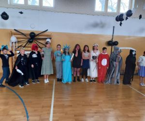 Uczniowie starszych klas w kolorowych przebraniach podczas wspólnego zdjęcia grupowego.