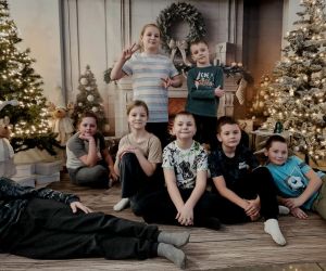 Dzieci z klas I–III pozujące w świątecznej scenerii pełnej choinek i dekoracji.