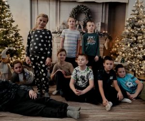  Uczniowie podczas sesji zdjęciowej na tle choinek i kominka.