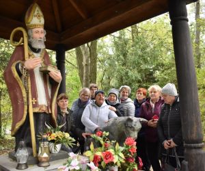 Kryłów -Kolonia. Figura św. Mikołaja, obok kamienny wilk, z tyłu grupa ludzi