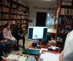 Grupa dzieci wraz z panią bibliotekarką w bibliotece.