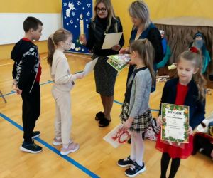 Pani Dyrektor i nauczycielka prowadząca konkurs wręczają dyplomy uczennicy klasy drugiej