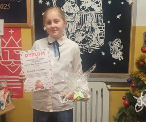 Uczennica trzyma dyplom i nagrodę