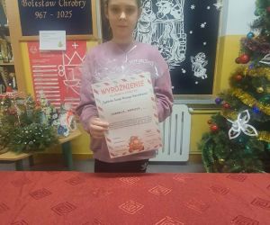 Uczennica trzyma dyplom i nagrodę