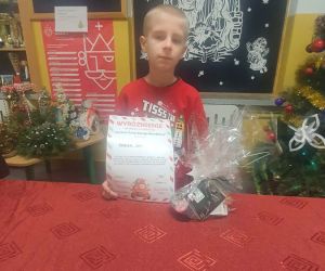 Uczeń trzyma dyplom i nagrodę
