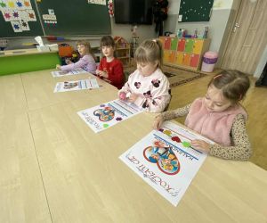 Kilka dziewczynek z oddziału przedszkolnego siedzi przy stoliku i ozdabia kalendarze, skupiając się na pracy plastycznej.