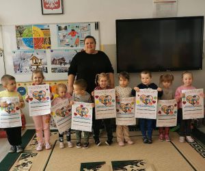 Dzieci z oddziału przedszkolnego stoją w szeregu razem z nauczycielką i trzymają w rękach gotowe kalendarze.