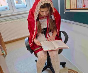 Uczennica klasy siódmej w stroju
Czerwonego Kapturka czyta baśń młodszym uczniom