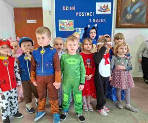 Dzieci z oddziału przedszkolnego pierwszego i drugiego na tle tablicy dekoracyjnej