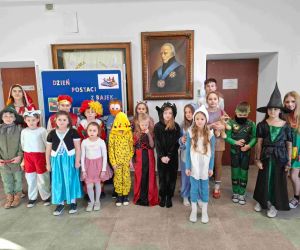 Uczniowie klas pierwszej, drugiej i trzeciej na tle tablicy dekoracyjnej