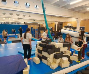 Uczniowie budują mur z piankowych klocków