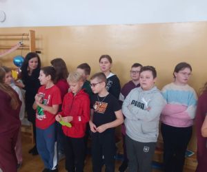 Grupa uczniów ustawiona wzdłuż ściany sali gimnastycznej.