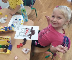 Dziewczynka uśmiecha się podczas malowania farbami