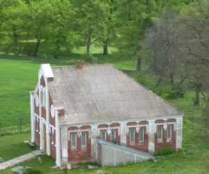 Czerwony budynek z białymi elementami, otoczony drzewami