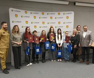 Finaliści konkursu stoją w rzędzie z dyplomami i nagrodami. Po bokach znajdują się przedstawiciele władz oraz organizatorzy wydarzenia.