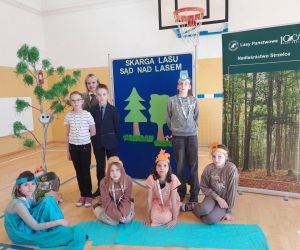 Uczniowie klasy czwartej z panią leśnik przy dekoracji na pamiątkowej fotografii