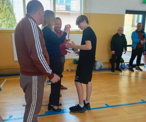 Pani Dyrektor, pan inspektor oświaty i nauczyciel wychowania fizycznego wręczają medal i dyplom uczniowi