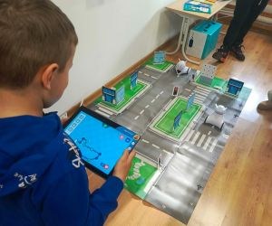 Chłopiec programuje robota poruszającego się na macie