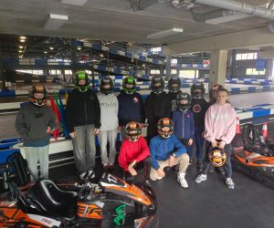 Uczniowie w kaskach stoją przy gokartach