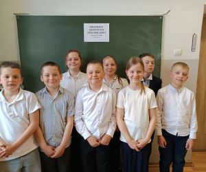 Uczniowie klasy III stoją razem przed tablicą po zakończonym sprawdzianie.