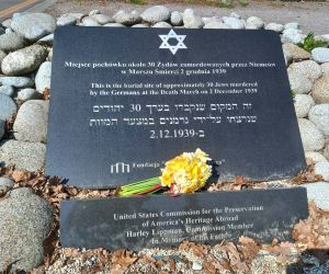 Zbliżenie na tablicę pamiątkową w Cichobórzu z napisem upamiętniającym ofiary oraz złożonym bukietem żonkili.