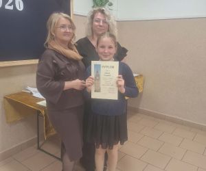 Uczennica odbiera dyplom podczas Gminnego Konkursu Języka Angielskiego w Husynnem, stoi wraz z organizatorkami wydarzenia.
