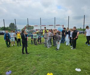 Uczniowie biorą udział w zabawie integracyjnej na boisku szkolnym.
