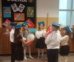 Uczniowie stoją w kółku i trzymają w ręku balony