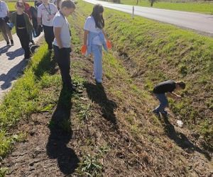 Uczniowie zbierają śmieci w rowie