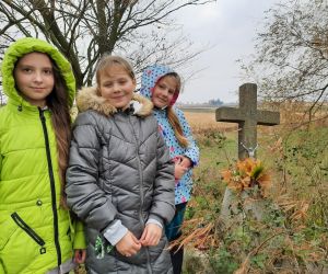 Uczennice stoją przy zbiorowej mogile z okresu I wojny światowej