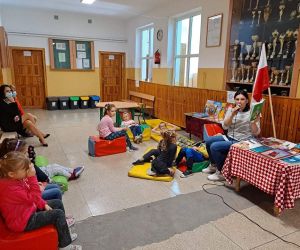 Nauczycielka czyta do mikrofonu, dzieci słuchają